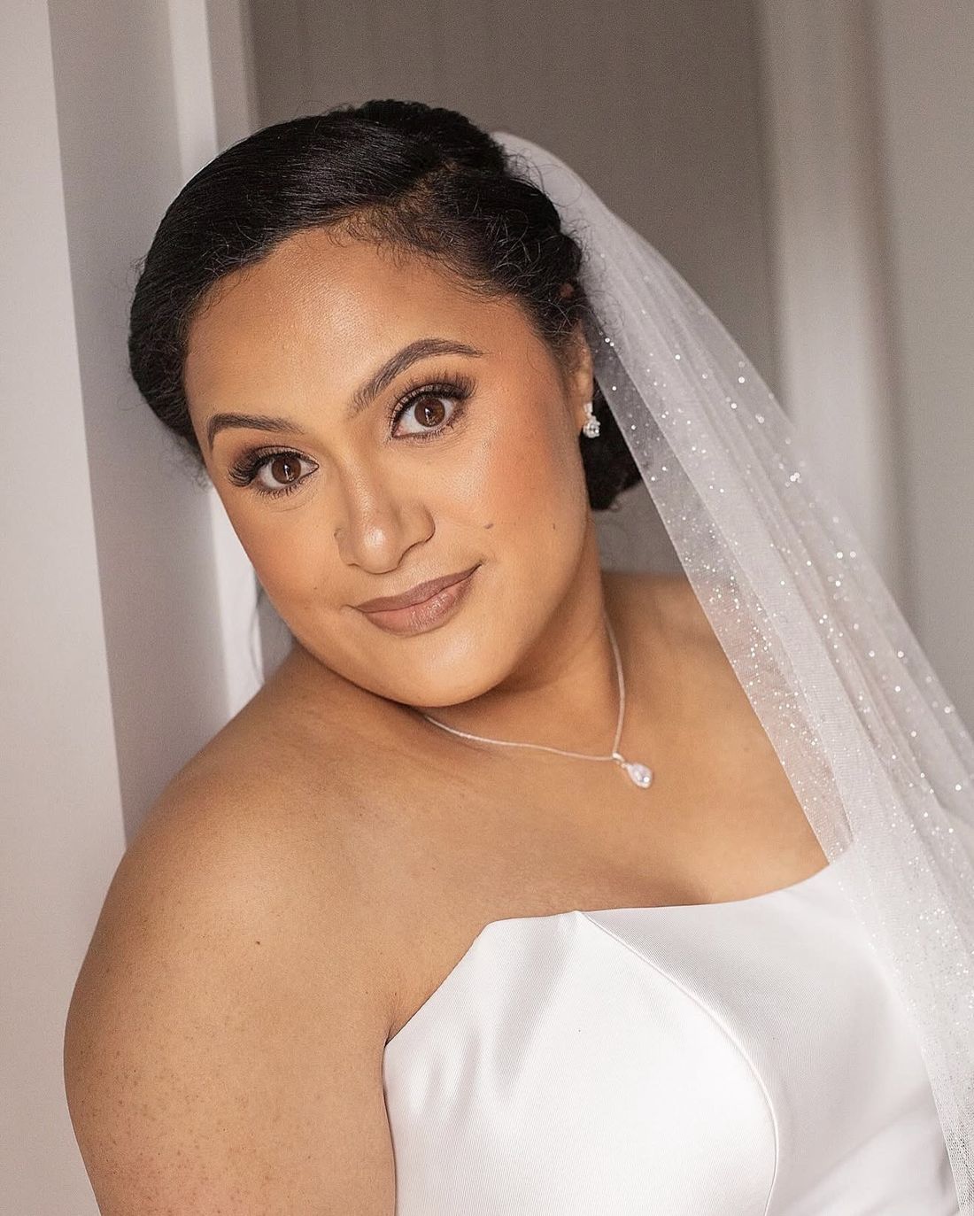 Bride with a sparkling veil, bronzed skin and a soft nude lip