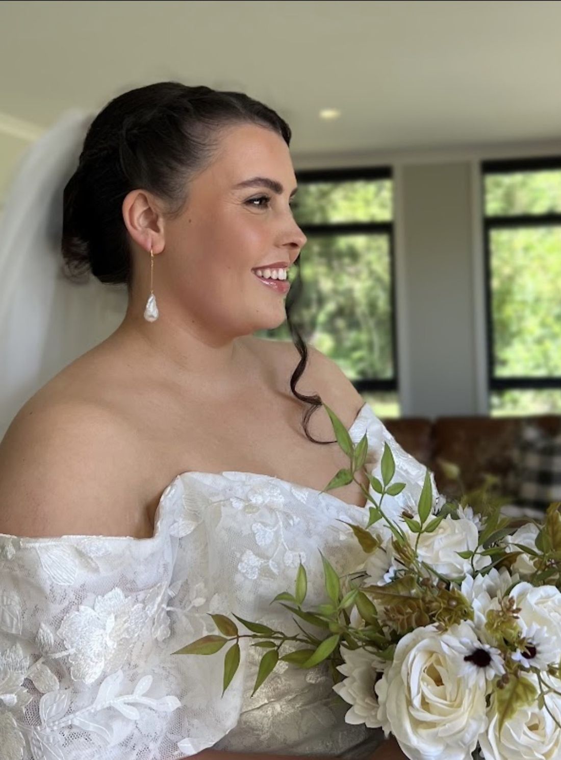 Smiling bride in an off-shoulder lace gown with a soft bronzed glow